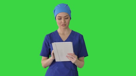 smiling female nurse using tablet computer walking and looking at camera on a green screen, chroma key