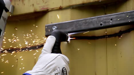 a hand clad in protective gloves is welding a metal structure - close up