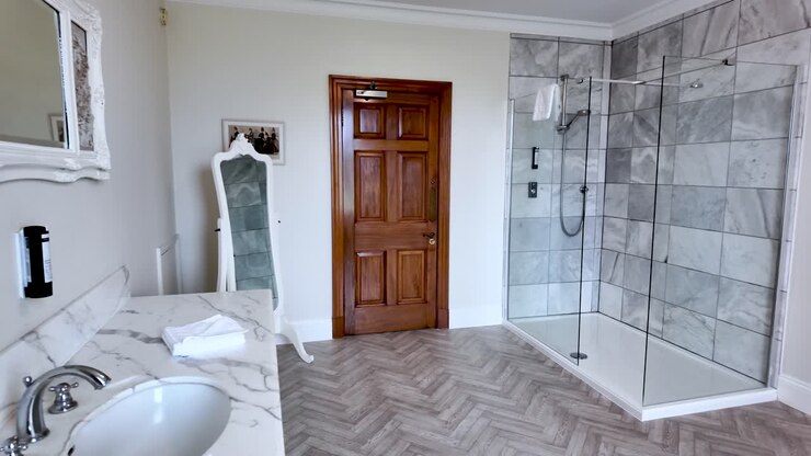 Spacious Bathroom Interior With Marble Countertop Herringbone Floor Walk-In Shower And Wooden Door For Real Estate And Interior Design Concepts