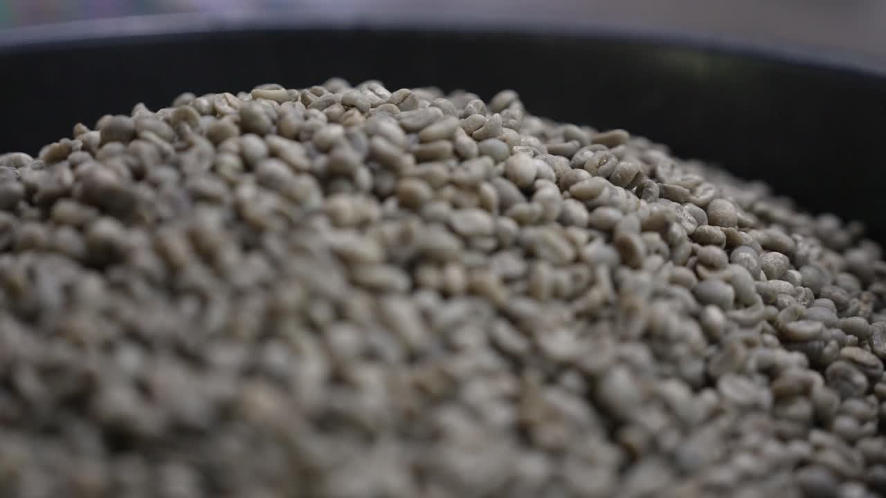 A closeup view of green coffee beans piled inside a large container