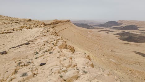 un drone che vola sopra un uomo mentre viaggia lungo il bordo del cratere ramon