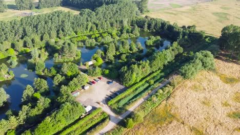 Aerial-View-Of-Fishing-Pond-And-Surrounding-Countryside-In-Norfolk,-England---aerial-drone-shot