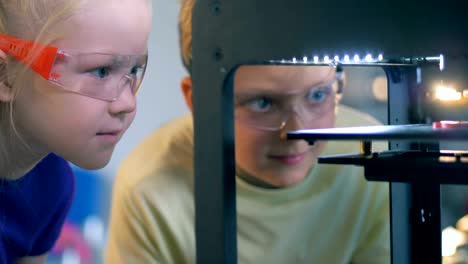 two agitated children are watching a scientific experiment with interest