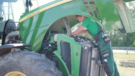 farmer mechanic repairing tractor. open tractor hood, engine. repair agricultural technology