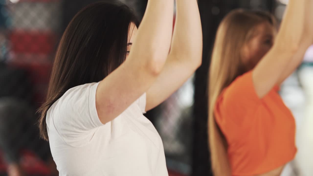 Close-up portrait of two young women exercising in gym with kettlebell