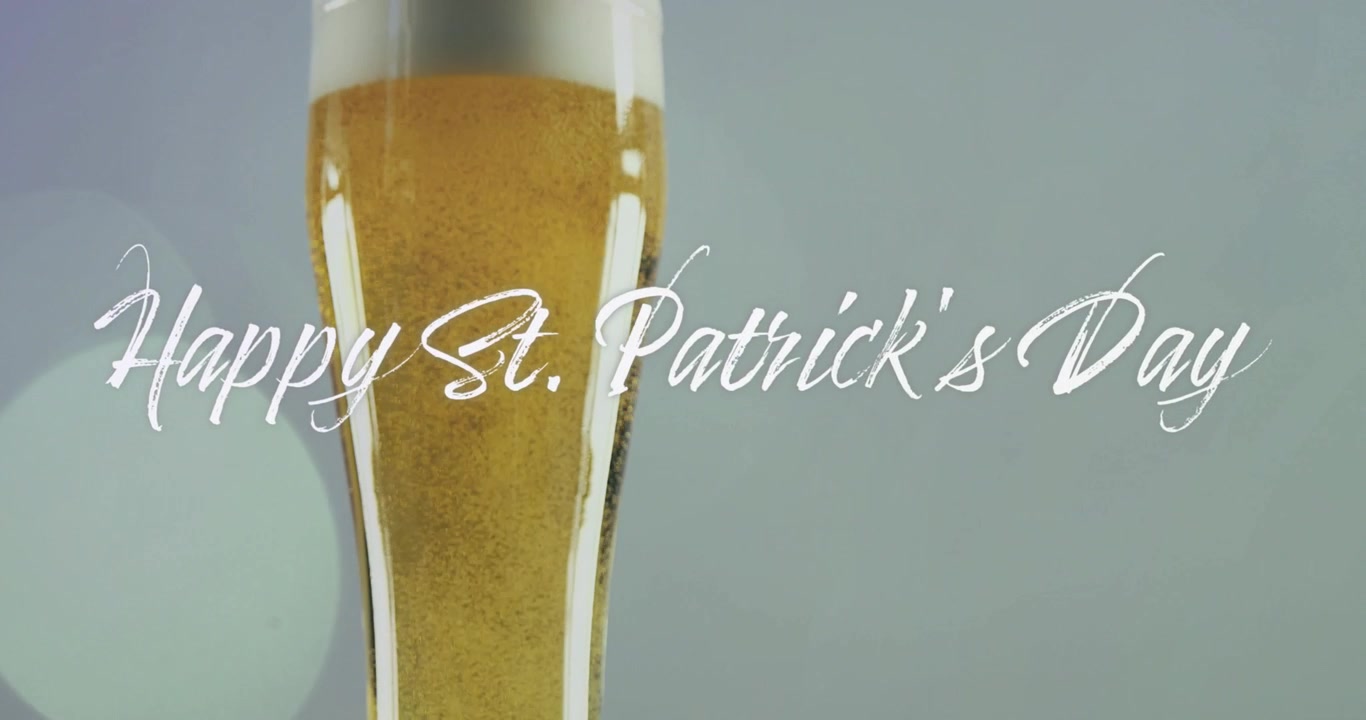 Versando birra in un alto bicchiere da pilsner, birra dorata con schiuma crescente, testo "Happy St Patrick's Day" che oscura.