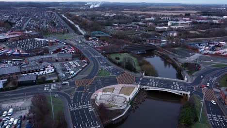 aerial early morning city street traffic commuting intersection lanes crossing curved river slow high tilt down