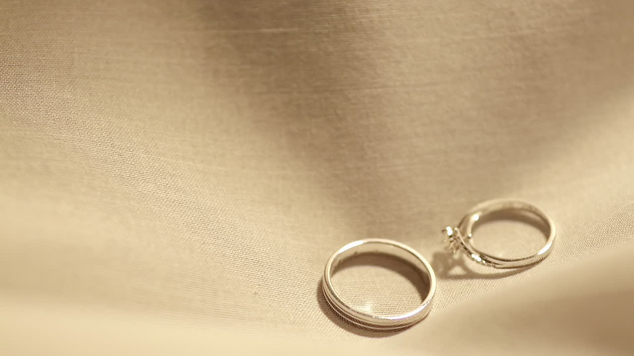 テーブルに敷かれた布の上に、プラチナとダイヤモンド製の婚約指輪のペアを落とす。