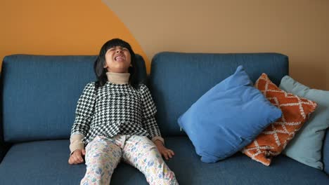 happy little girl laughing on a blue sofa