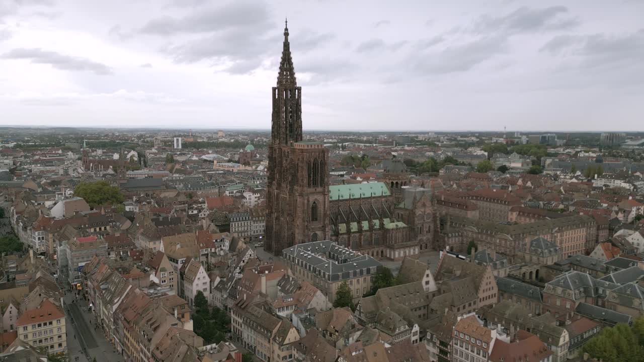 Vista aerea del centro storico di Strasburgo con la maestosa Cattedrale di Strasburgo che domina i tetti medievali sotto un cielo cupo e nuvoloso.