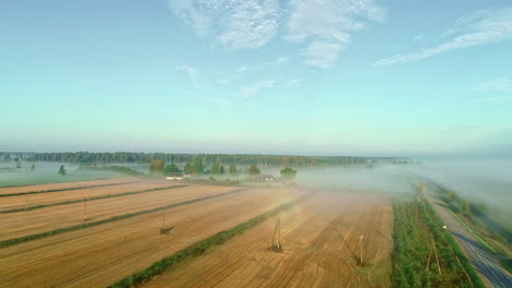 aerial perspective of a fog-covered plowed cropland on a sunny day