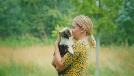 mujer de mediana edad con un cachorro en sus brazos se encuentra en la lluvia torrencial de verano momentos inolvidables o