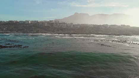 Toma-Cinematográfica-De-Un-Dron-Siguiendo-Una-Ola-Recién-Formada-Que-Se-Acerca-A-Una-Costa-Rocosa-Con-Casas-Frente-A-La-Playa-En-Una-Tranquila-Ciudad-Costera-De-Vermont-Que-Muestra-Una-Sensación-De-Vacaciones,-Jubilación-O-Vida-De-Lujo.