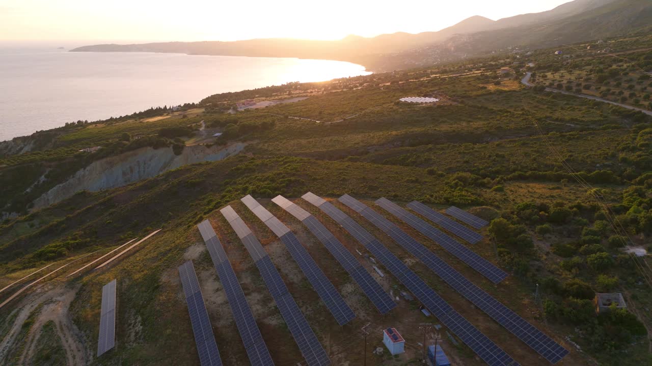 Stunning aerial drone view of solar power photovoltaic panels set against a dramatic sunset in Kefalonia, Greece. The renewable energy installation contrasts beautifully with the natural landscape.