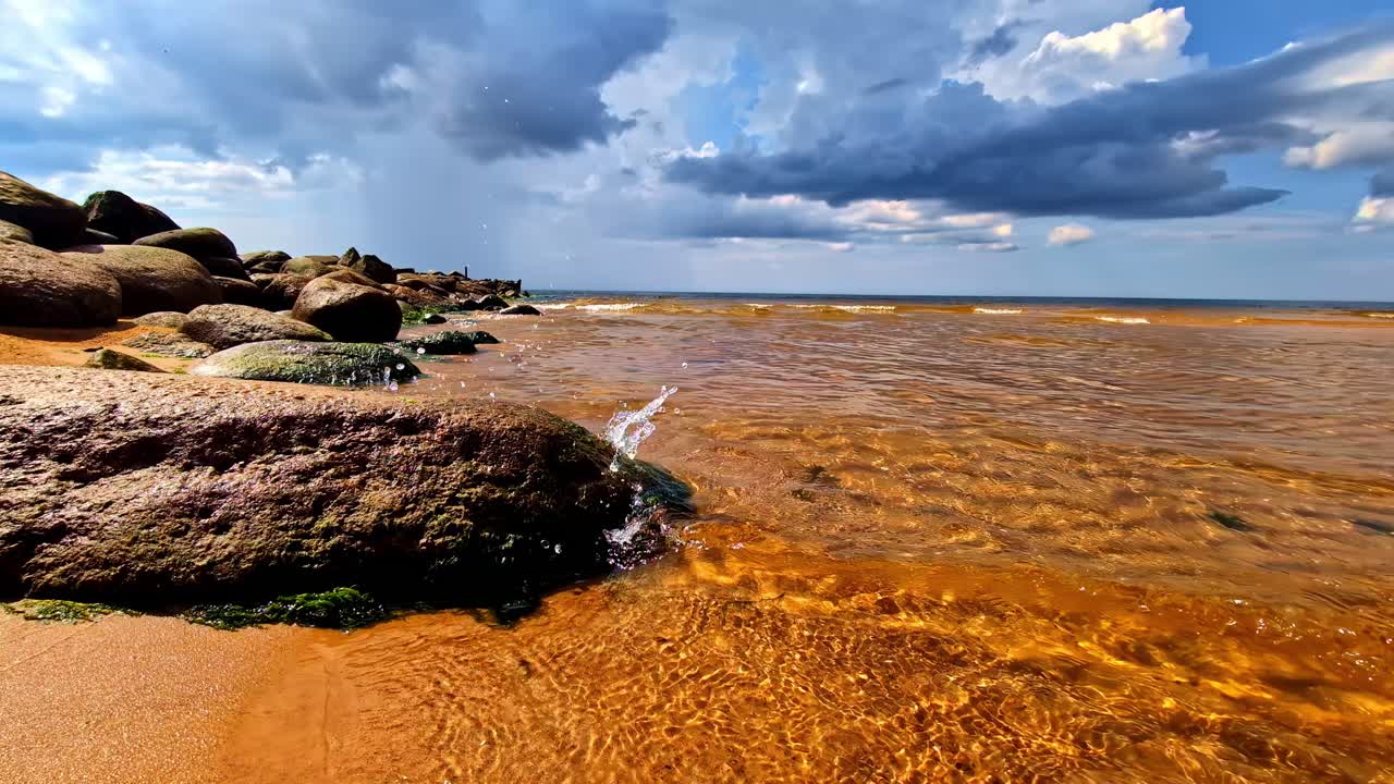Coastal Shoreline With Rocks and Waves Under Dramatic Summer Sky in Latvia
