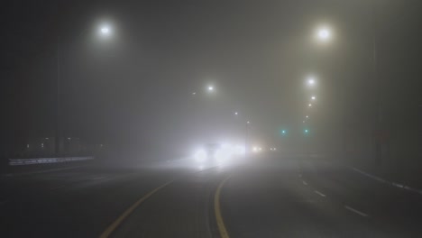 los coches conducen por la carretera en una noche de niebla