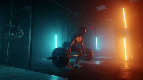 muscular fitness man doing push a barbell over his head in modern fitness center. functional training. snatch exercise. slow motion color led light saturated bright colors