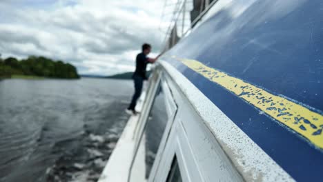 person walking on boat gunwale, dynamic side angle on water