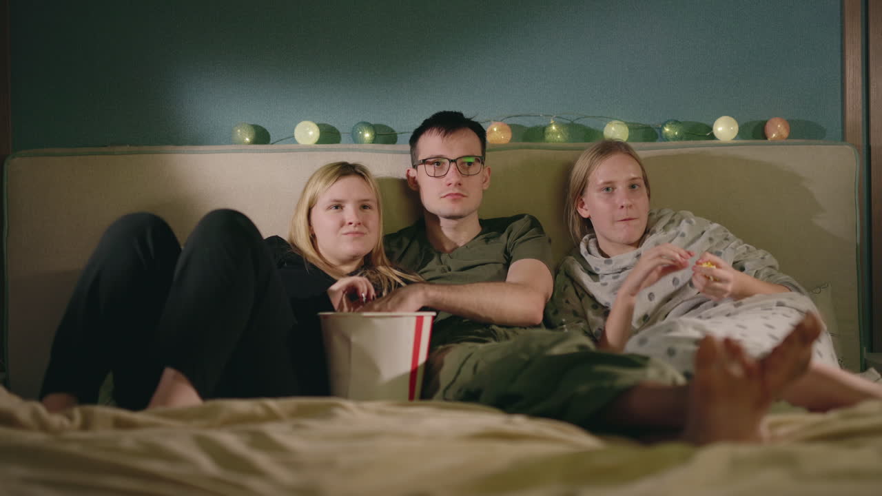 amigos viendo una película en la cama