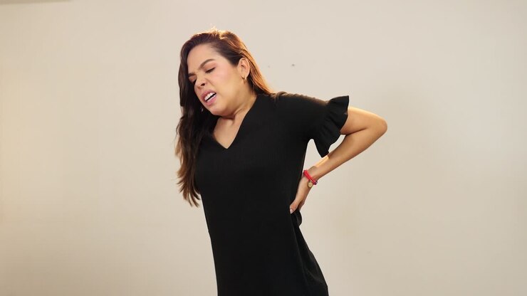 Young woman with back pain stretching her body
