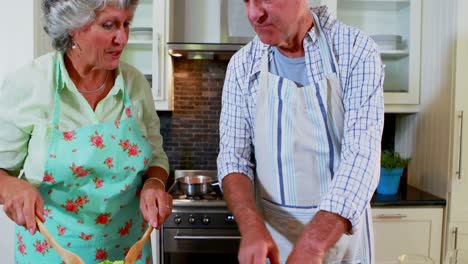 Senior-couple-preparing-salad-in-kitchen-4k