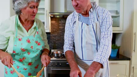 pareja de alto nivel preparando ensalada en la cocina 4k