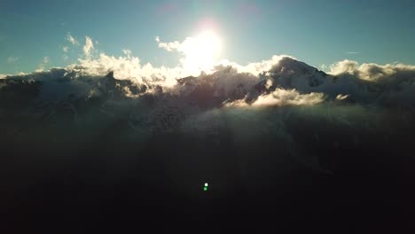 aerial view of sun rays through a cloudscape over austrian mountains snowy peaks