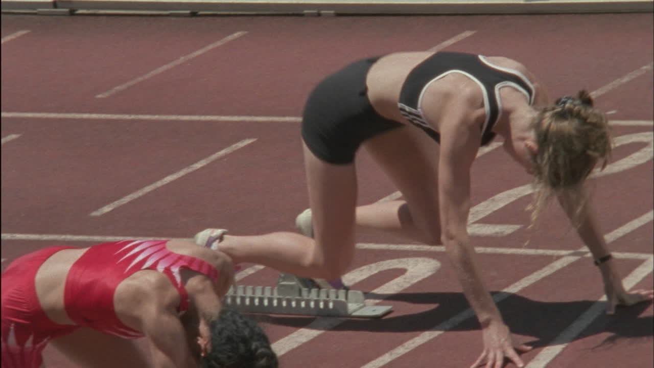 여러 명의 여성 주자가 트랙의 시작 블록을 떠납니다.