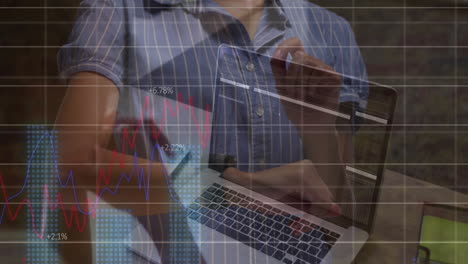 using laptop with financial graphs and data, person creating animation in school