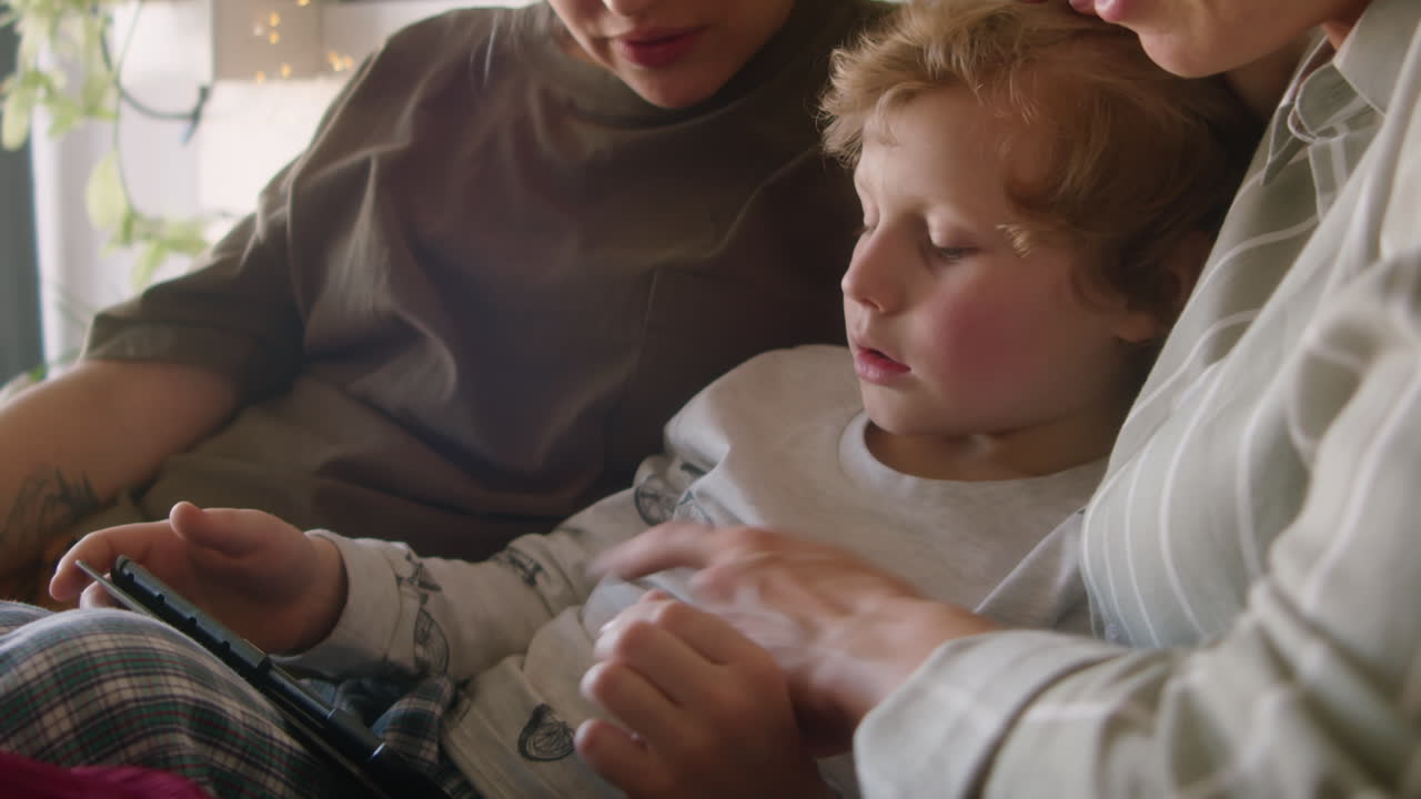 Little Boy Using Tablet and Chatting with Lesbian Mothers on Bed