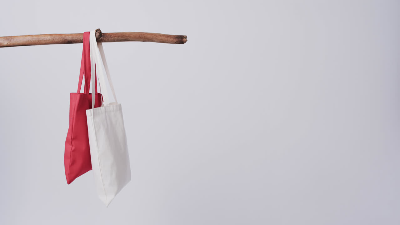 video de bolsas de lona rojas y blancas colgando de la rama con espacio de copia en un fondo blanco