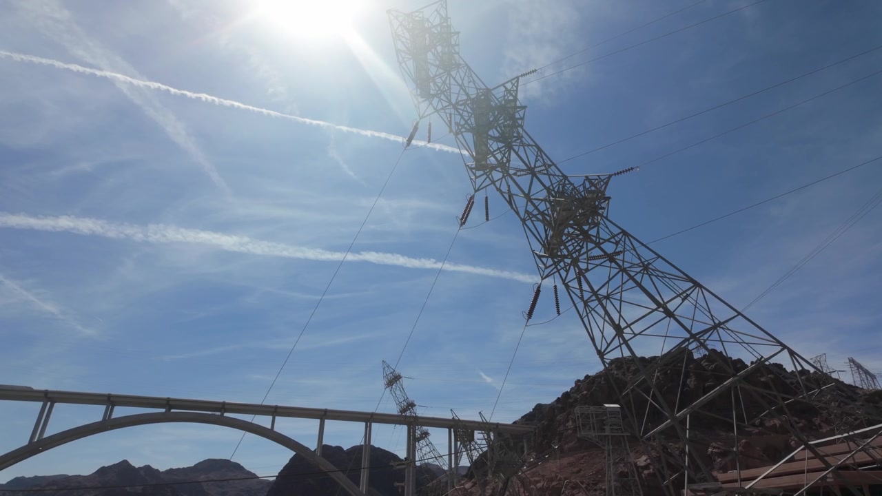 As torres de transmissão anguladas na Barragem Hoover, inclinadas sobre o Rio Colorado, transmitindo a energia hidrelétrica.