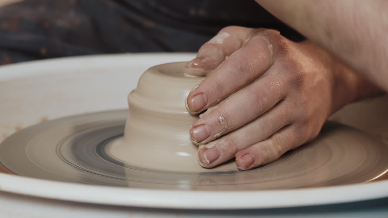 manos moldeando arcilla en una rueda de cerámica