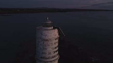 stunning aerial circling around majestic lighthouse at evening dusk, shine light