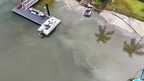 aerial view of a sand dredging operation with boats and equipment in a river setting under natural daylight