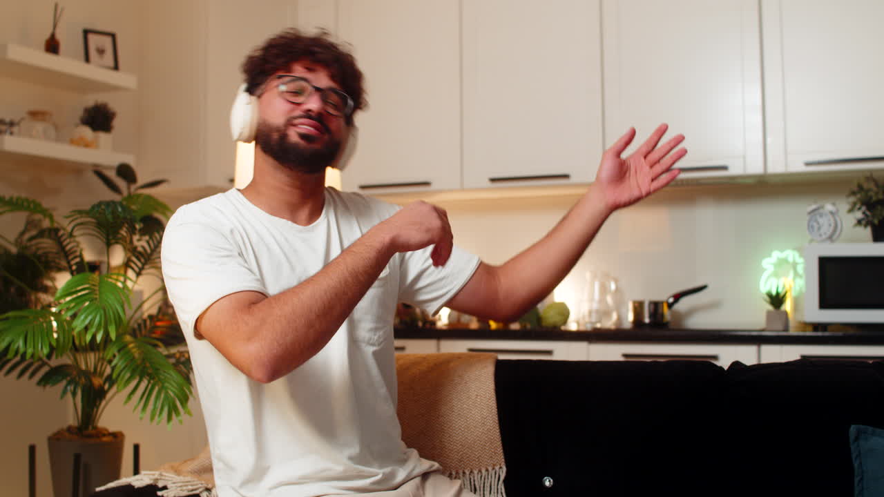 Uomo arabo seduto che suona l'air guitar, balla rock'n'roll, ride, pieno di energia e divertimento, in una serata musicale al chiuso, entusiasta.