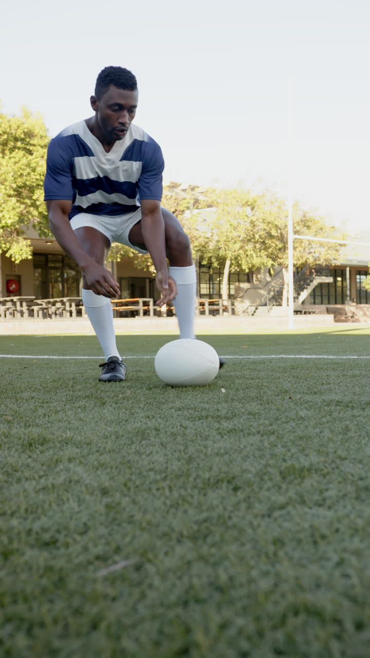 Vertical video: Rugby player in action, preparing to kick ball on outdoor field