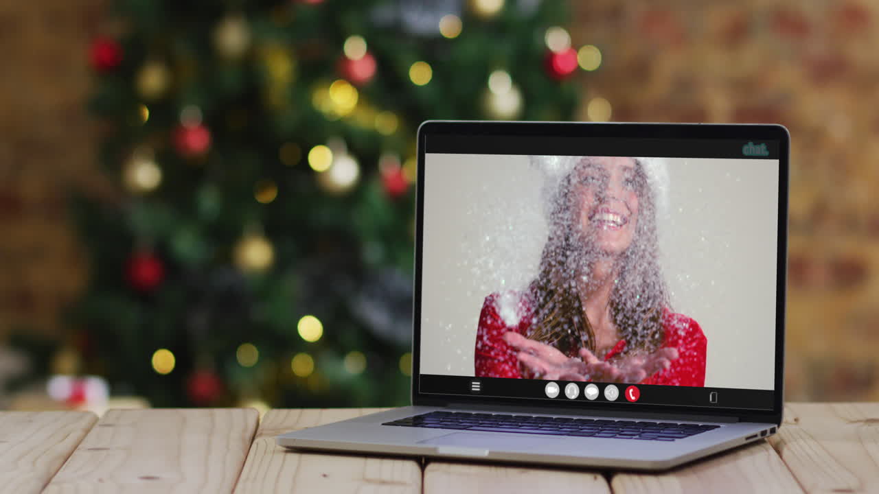 feliz mujer caucásica en disfraz de santa en videollamada en computadora portátil, con decoraciones de navidad y árbol