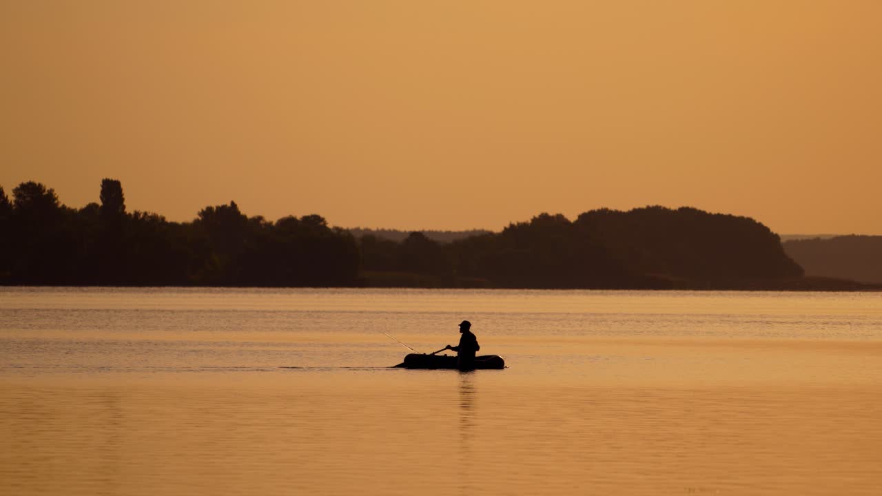 Fisherman on boat against sunset. Fisherman with a fishing rod at sunset
