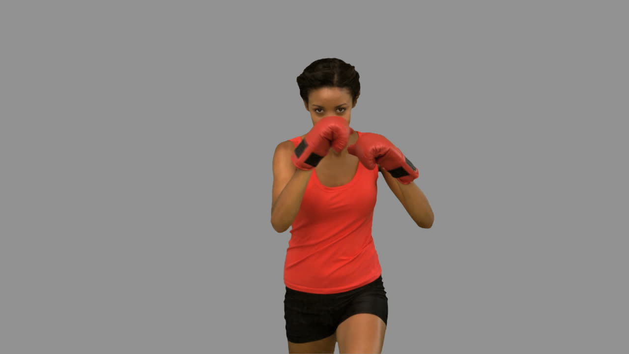 Woman performing high kick on grey screen