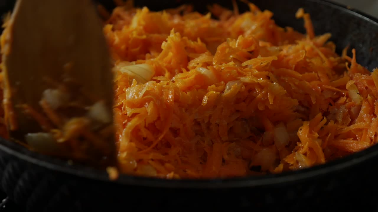 freír cebollas y zanahorias ralladas en una sartén con aceite. revolver freír en una bandeja con una espátula de madera