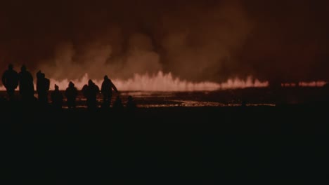 silhouettes of people observing the fiery eruption of grindavik volcano in sundhnúkur crater, iceland, at night