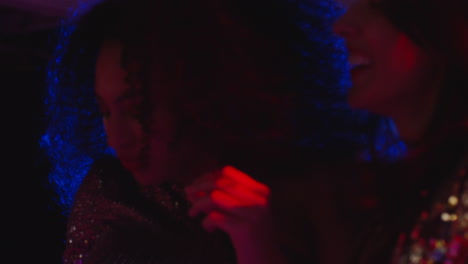 close up of two women in nightclub bar or disco dancing with sparkling lights 10