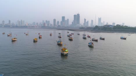 flying over the fishermen's boats parked at the koliwada next to worli fort, revealing the mumbai cityscape view of skyscrapers in the back with settlements to contrast