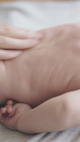 sleeping infant boy lies on baby changing table and nurse practices hypertonus back massage actively close view