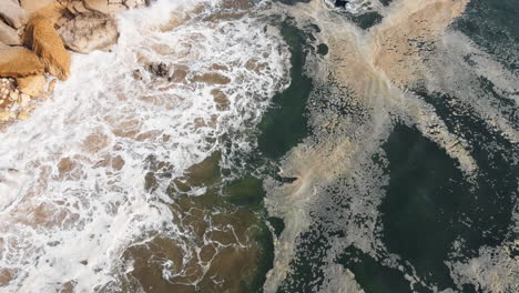 vista aérea de una playa rocosa con olas estrelladas en nazare, portugal