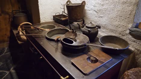 a shoot of a wood stove with pans on it, inside a house from the 1800s