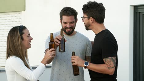 hombre joven sonriente con cerveza caminando a través de la puerta a los amigos