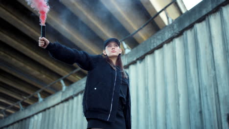 woman with smoke bomb in hand looking at camera. girl standing on urban street