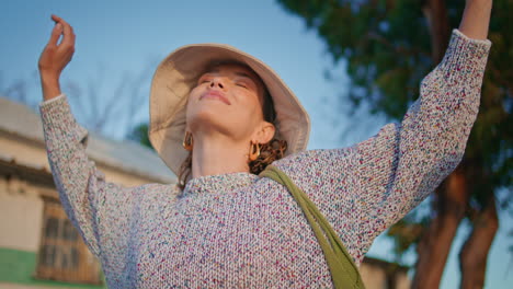 outdoors girl spreading arms in golden sunlight closeup. happy woman close eyes